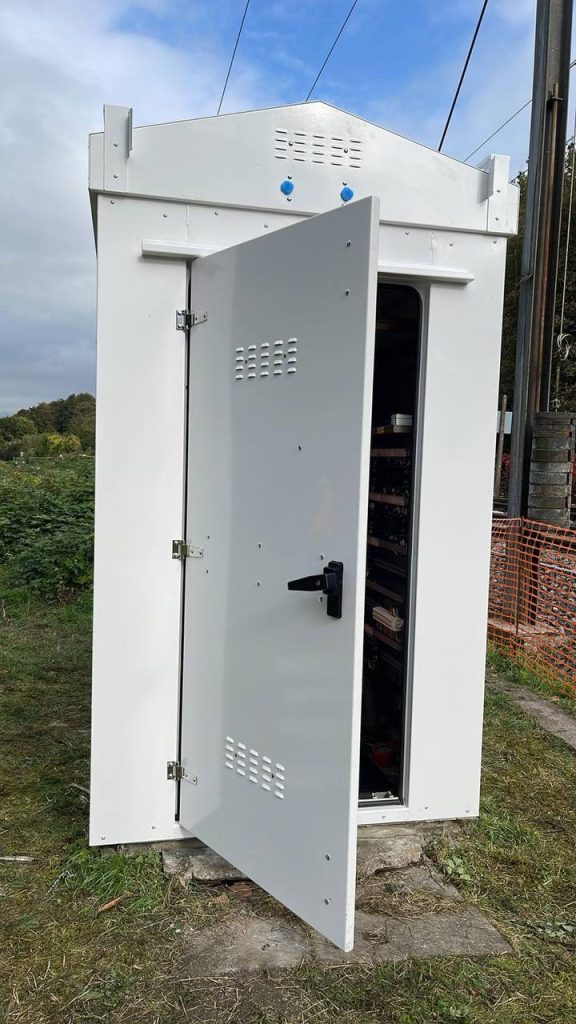 New cabinet built around the live rack with the door open on the equipment